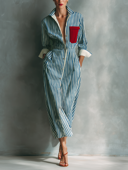 Blue And White - A woman wearing a blue and white vertically striped cotton maxi shirt dress with a contrasting red chest pocket, pointed collar, button-down front, and rolled-up white cuffs.