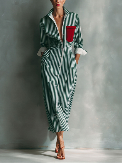Green And White - A woman wearing a blue and white vertically striped cotton maxi shirt dress with a contrasting red chest pocket, pointed collar, button-down front, and rolled-up white cuffs.