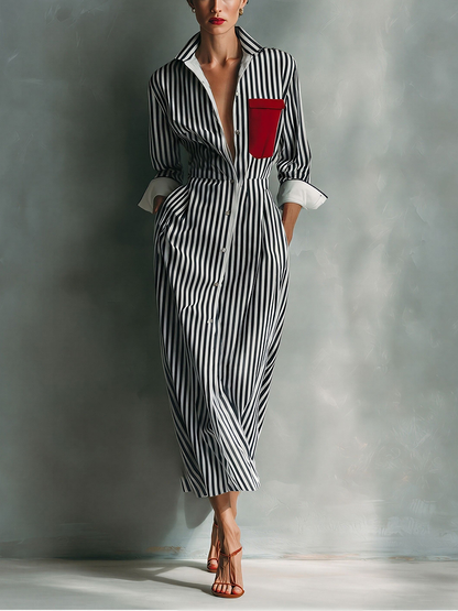 Black And White - A woman wearing a blue and white vertically striped cotton maxi shirt dress with a contrasting red chest pocket, pointed collar, button-down front, and rolled-up white cuffs.
