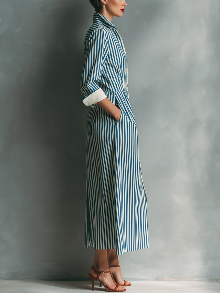 Black And White - A woman wearing a blue and white vertically striped cotton maxi shirt dress with a contrasting red chest pocket, pointed collar, button-down front, and rolled-up white cuffs.