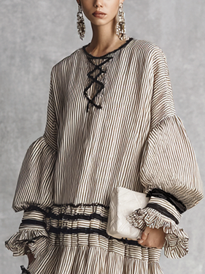 brown and white - A model wearing a voluminous, long-sleeved tiered maxi dress featuring vertical stripes, a lace-up neckline, balloon sleeves, and black ruffled trim along the tiers.