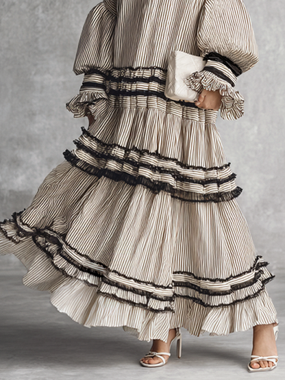brown and white - A model wearing a voluminous, long-sleeved tiered maxi dress featuring vertical stripes, a lace-up neckline, balloon sleeves, and black ruffled trim along the tiers.