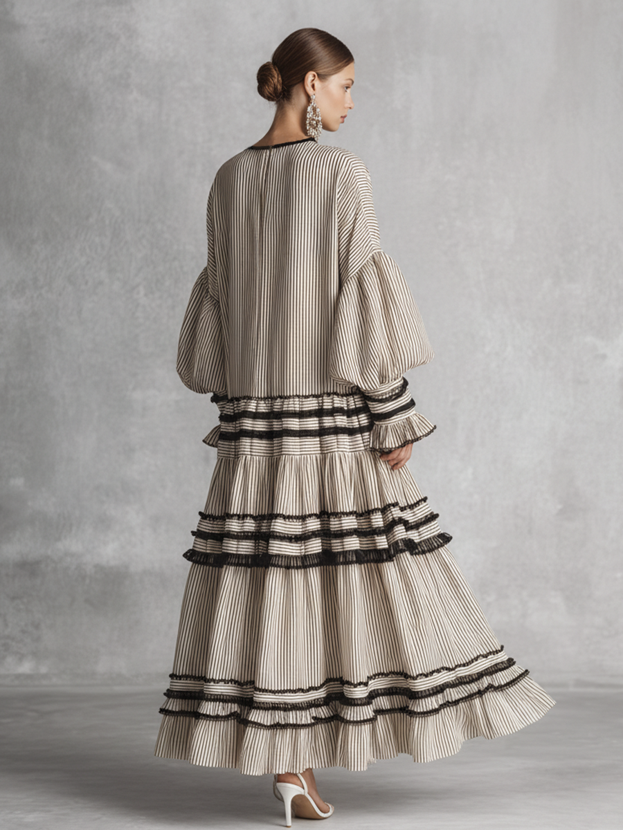 brown and white - A model wearing a voluminous, long-sleeved tiered maxi dress featuring vertical stripes, a lace-up neckline, balloon sleeves, and black ruffled trim along the tiers.
