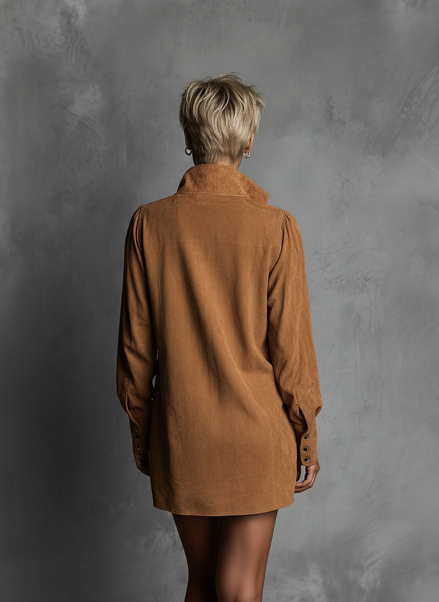 Brown - A model wears a tan suede-textured mini dress featuring a high stand collar, a deep V-neckline with embroidered border detailing, long sleeves, and side pockets against a textured grey background.