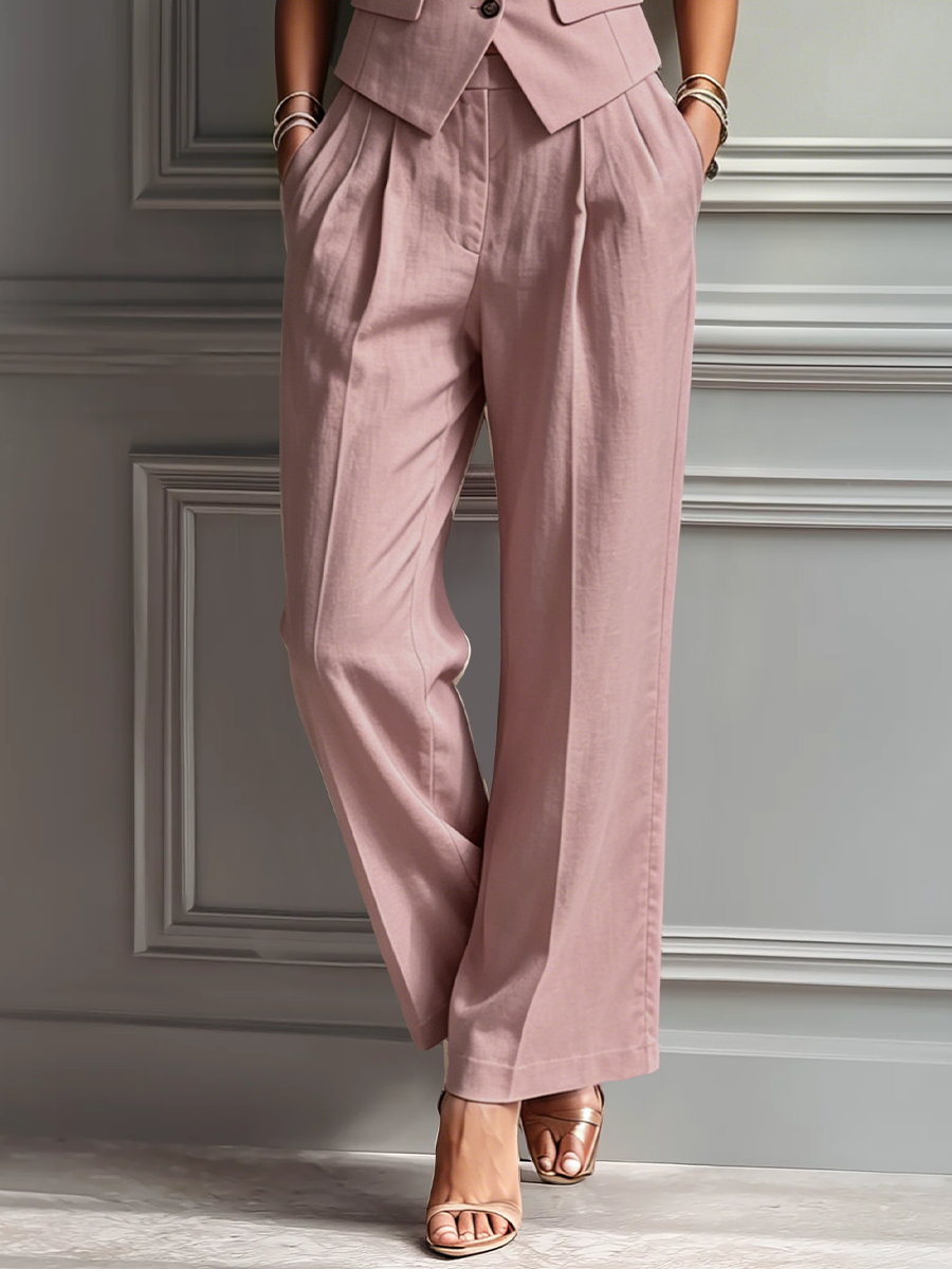 Blush Pink - A woman posing in a dusty pink tailored two-piece set featuring a sleeveless button-up waistcoat with lapels and matching high-waisted wide-leg trousers.