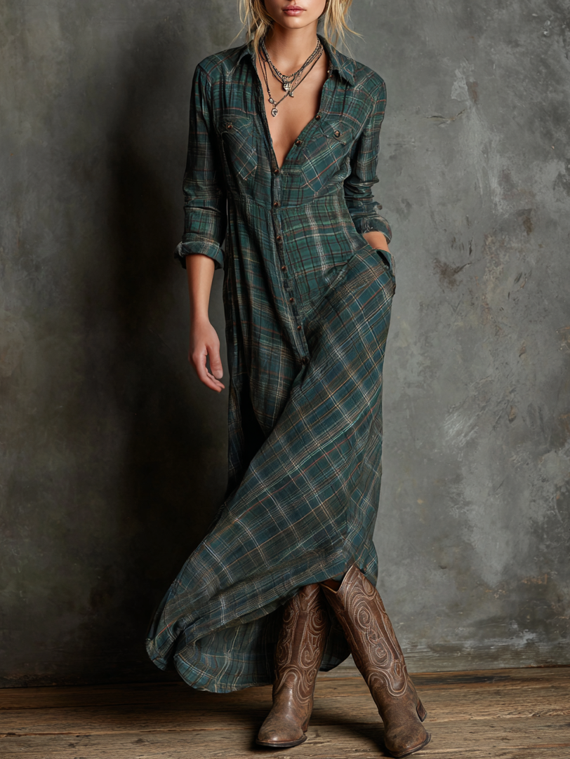 Green - A woman wearing a green and brown tartan plaid maxi shirt dress with a button-down front, long sleeves rolled up, and chest pockets, paired with brown leather cowboy boots against a textured grey wall.