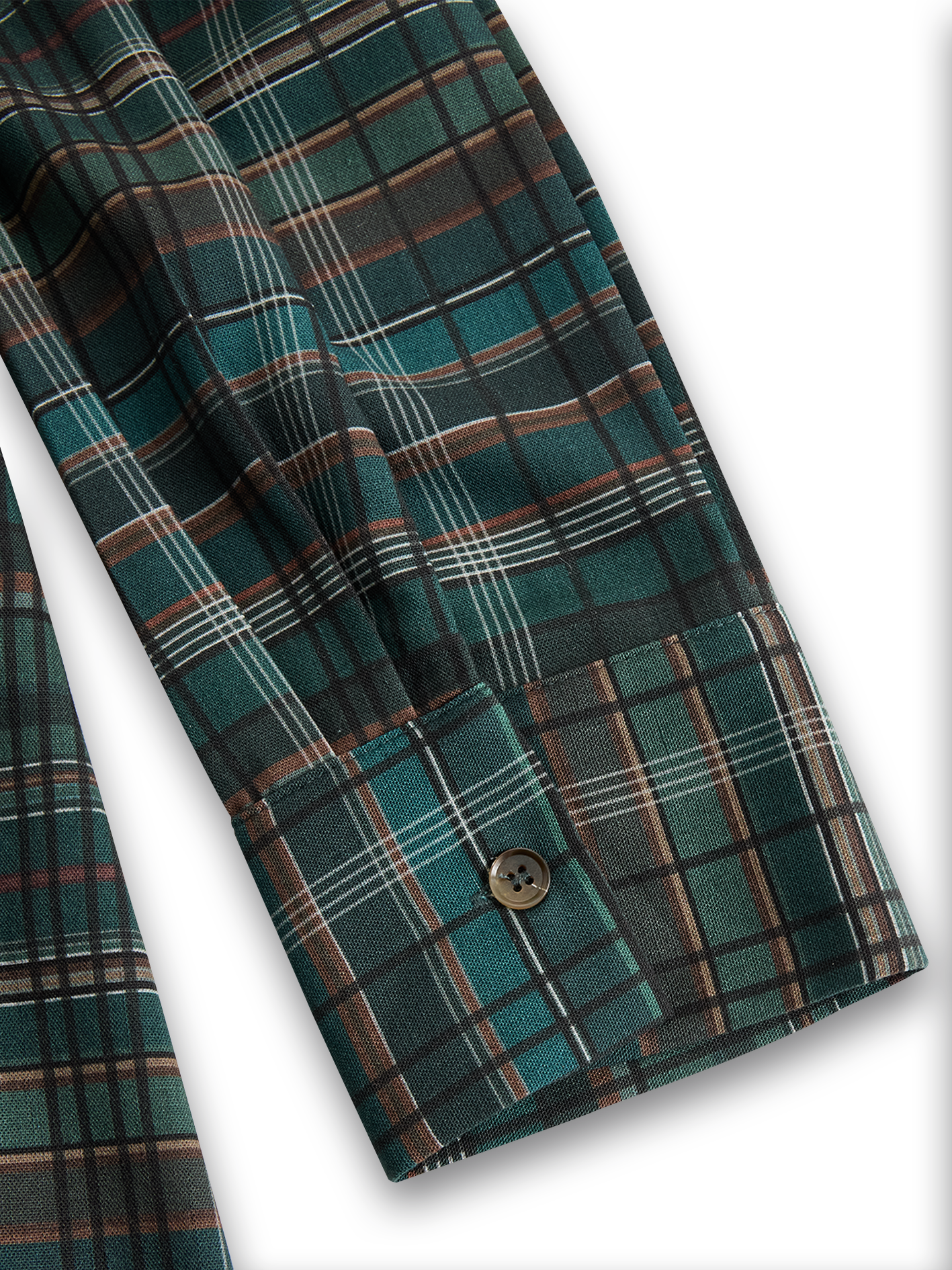 Black - A woman wearing a green and brown tartan plaid maxi shirt dress with a button-down front, long sleeves rolled up, and chest pockets, paired with brown leather cowboy boots against a textured grey wall.