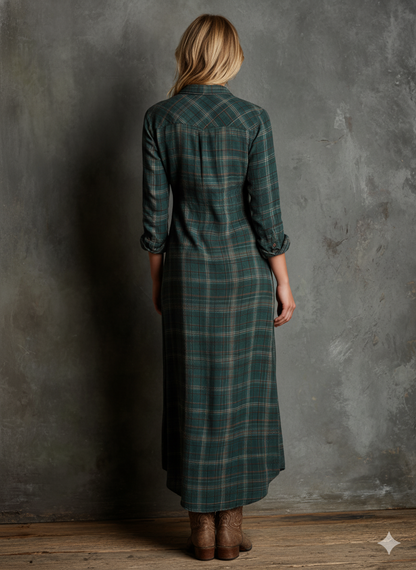 Red - A woman wearing a green and brown tartan plaid maxi shirt dress with a button-down front, long sleeves rolled up, and chest pockets, paired with brown leather cowboy boots against a textured grey wall.
