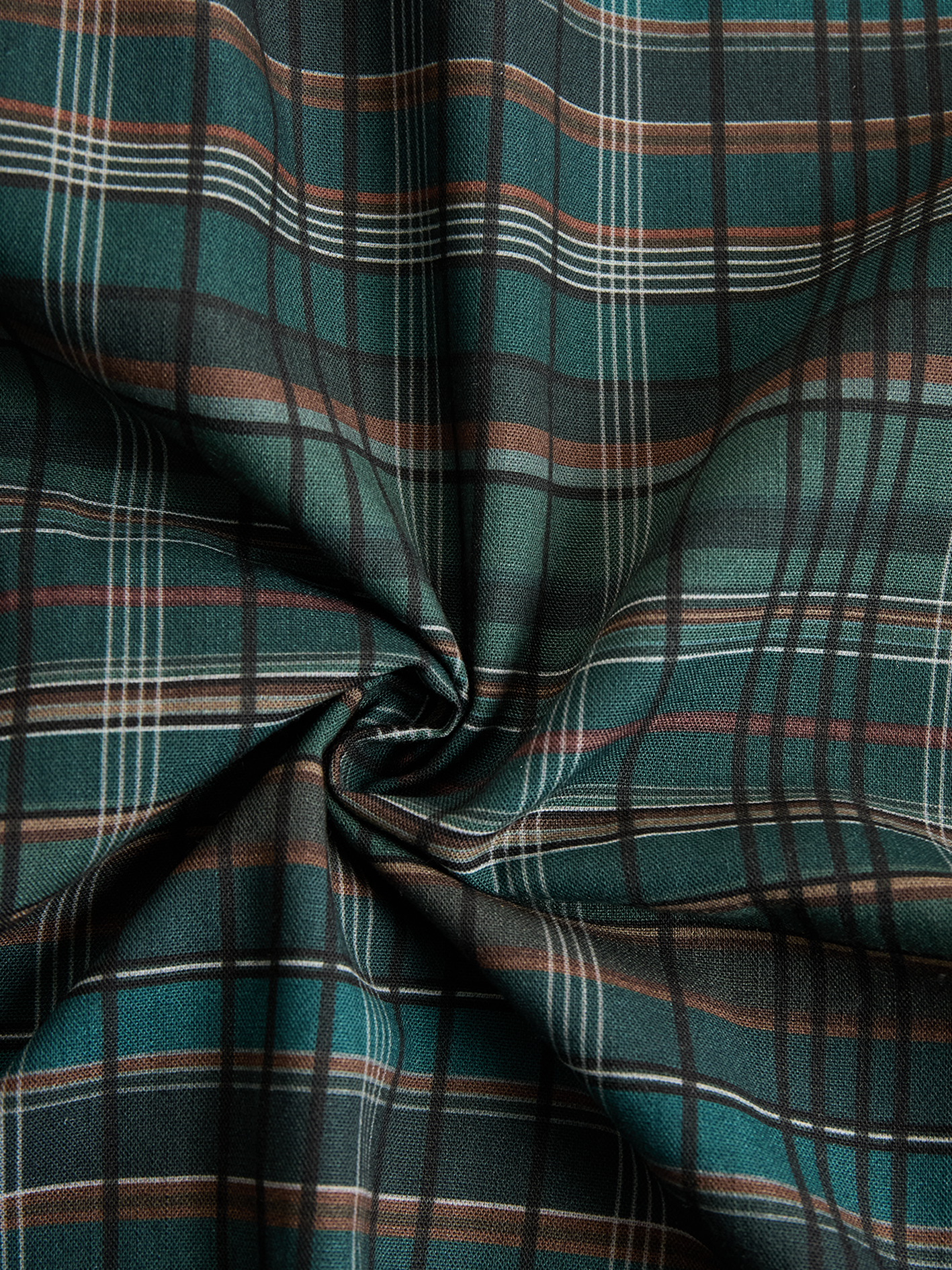 Black - A woman wearing a green and brown tartan plaid maxi shirt dress with a button-down front, long sleeves rolled up, and chest pockets, paired with brown leather cowboy boots against a textured grey wall.