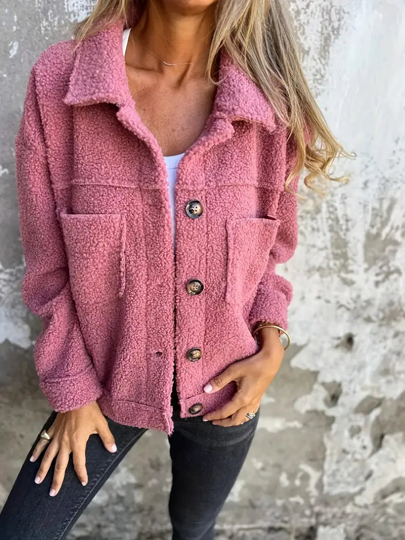 Pink - A woman wearing a pink, textured teddy fleece shacket with large buttons and chest patch pockets, styled casually over a white top and dark jeans.