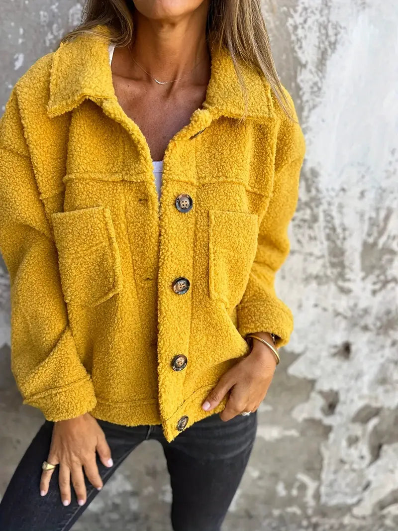 Yellow - A woman wearing a pink, textured teddy fleece shacket with large buttons and chest patch pockets, styled casually over a white top and dark jeans.