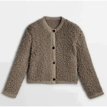 Brown - A woman wearing a beige, textured boucle knit cardigan with a button-front closure, ribbed trims, and gold-tone buttons, styled casually over a white top and light blue jeans.