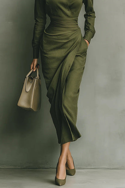 2XL - A woman wearing an elegant olive green textured midi dress with a pointed collar, long sleeves, a highly cinched ruched waist, and a draped wrap skirt with a side pocket.