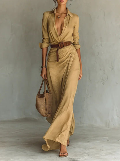 Khaki - A woman wearing a sand-coloured, textured crepe maxi shirt dress with a plunging collared neckline, ruched waist detailing, and a draped wrap-effect skirt.