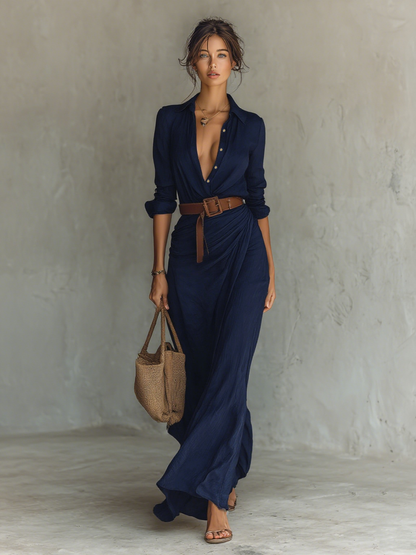 Navy - A woman wearing a sand-coloured textured crepe maxi shirt dress with a collared neckline, unbuttoned front, ruched draped waist, and long sleeves, accessorised with a brown leather belt.