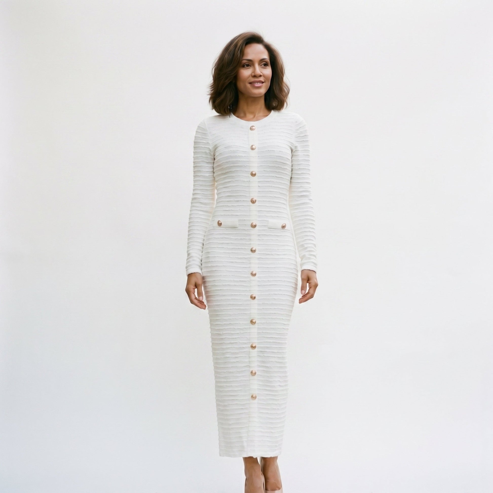 White - A woman wearing a long-sleeve black textured knit column midi dress featuring gold-tone buttons down the front and a pointelle hem, set against a plain white background.