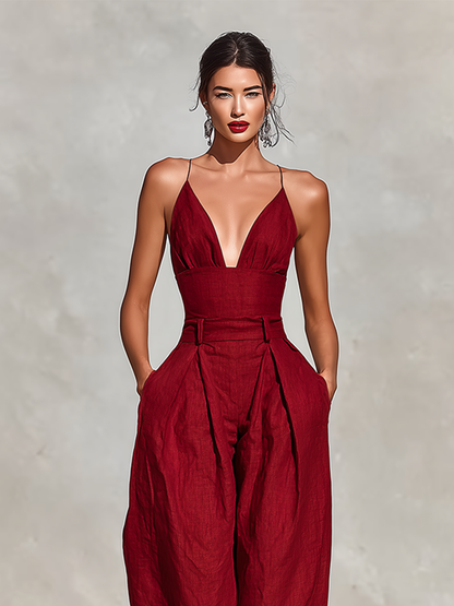 Red - A model wearing a deep red, textured linen wide-leg jumpsuit featuring a plunging V-neckline, structured high waist, and pleated trousers.