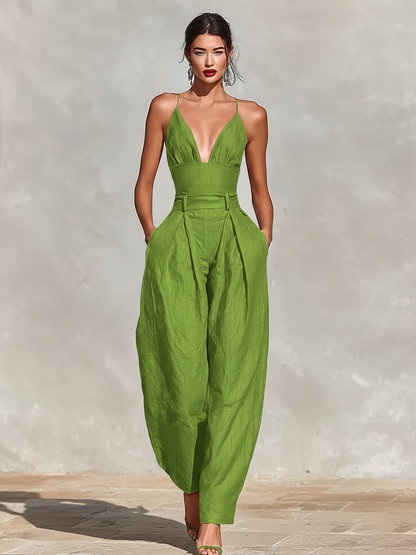 Green - A model wearing a deep red, textured linen wide-leg jumpsuit featuring a plunging V-neckline, structured high waist, and pleated trousers.