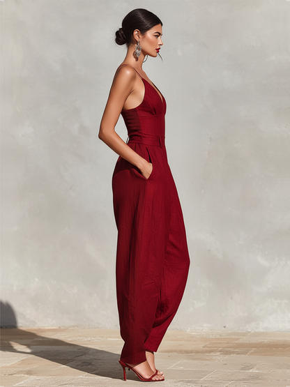 Green - A model wearing a deep red, textured linen wide-leg jumpsuit featuring a plunging V-neckline, structured high waist, and pleated trousers.