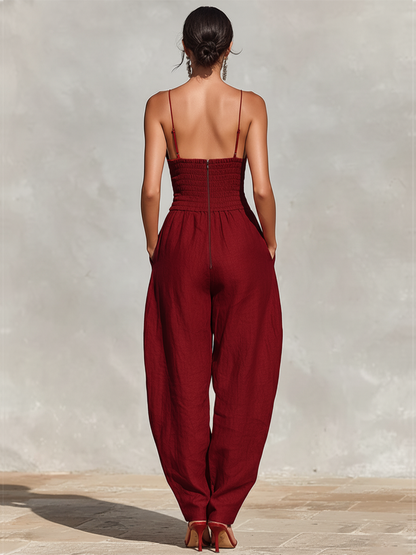 Green - A model wearing a deep red, textured linen wide-leg jumpsuit featuring a plunging V-neckline, structured high waist, and pleated trousers.
