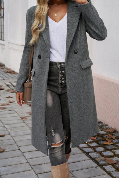 Gray - A woman wearing a grey textured mid-length coat with notch lapels and flap pockets, styled over a white V-neck t-shirt and distressed grey jeans.