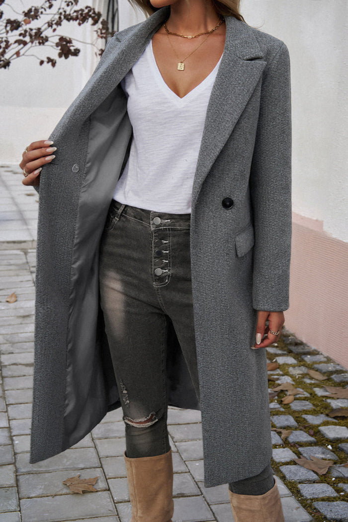 Gray - A woman wearing a grey textured mid-length coat with notch lapels and flap pockets, styled over a white V-neck t-shirt and distressed grey jeans.