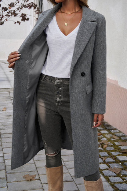 Gray - A woman wearing a grey textured mid-length coat with notch lapels and flap pockets, styled over a white V-neck t-shirt and distressed grey jeans.