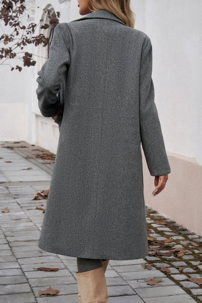 Gray - A woman wearing a grey textured mid-length coat with notch lapels and flap pockets, styled over a white V-neck t-shirt and distressed grey jeans.