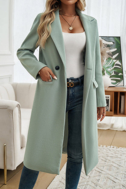 Green - A woman wearing a grey textured mid-length coat with notch lapels and flap pockets, styled over a white V-neck t-shirt and distressed grey jeans.
