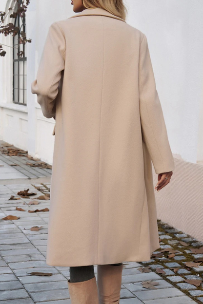 Beige - A woman wearing a grey textured mid-length coat with notch lapels and flap pockets, styled over a white V-neck t-shirt and distressed grey jeans.