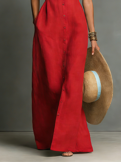 Black - A woman wearing a sleeveless red maxi dress with a point collar, button-down front, and side pockets, holding a wide-brimmed straw hat.