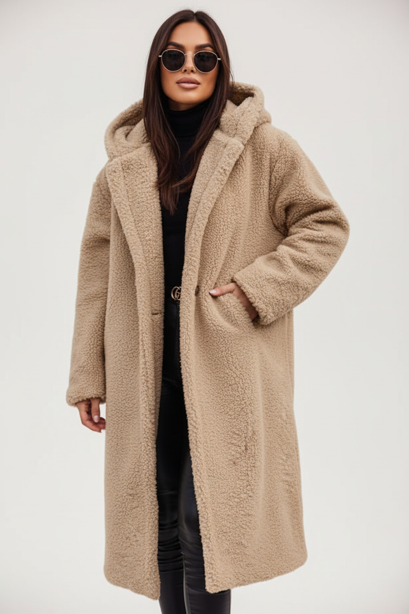 Beige - A woman wearing a mid-length olive green textured teddy coat with a large hood, styled over a black turtleneck sweater and black sunglasses against a plain white background.