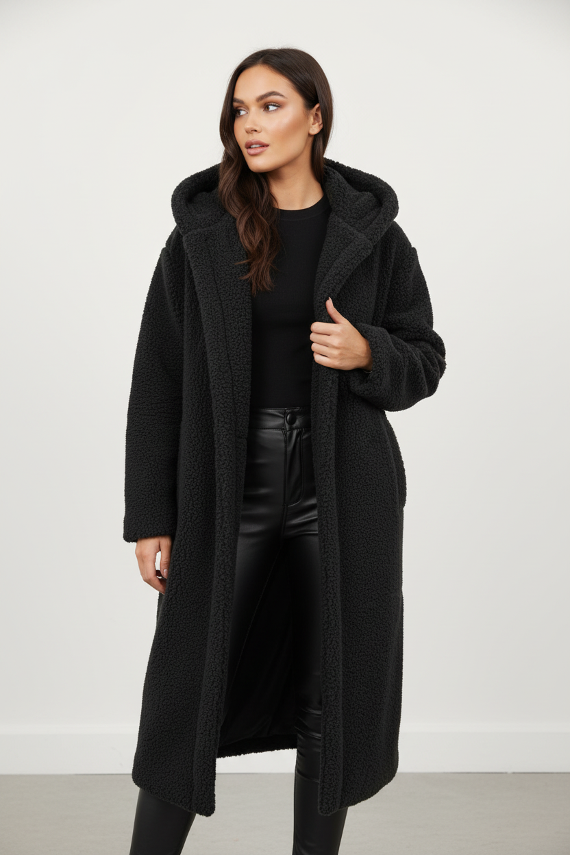 Black - A woman wearing a mid-length olive green textured teddy coat with a large hood, styled over a black turtleneck sweater and black sunglasses against a plain white background.