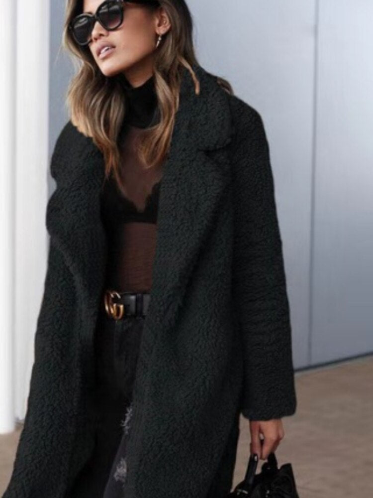 Black - A woman wearing a cream-coloured, longline textured teddy coat with oversized lapels, styled over a grey t-shirt and blue jeans.