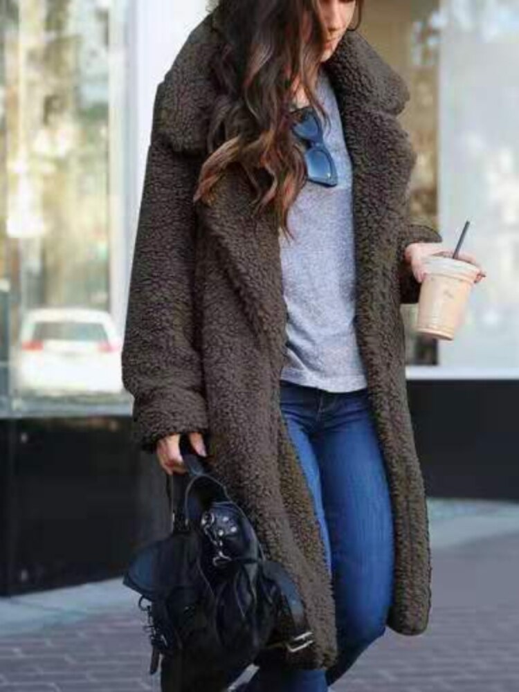 Black - A woman wearing a cream-coloured, longline textured teddy coat with oversized lapels, styled over a grey t-shirt and blue jeans.