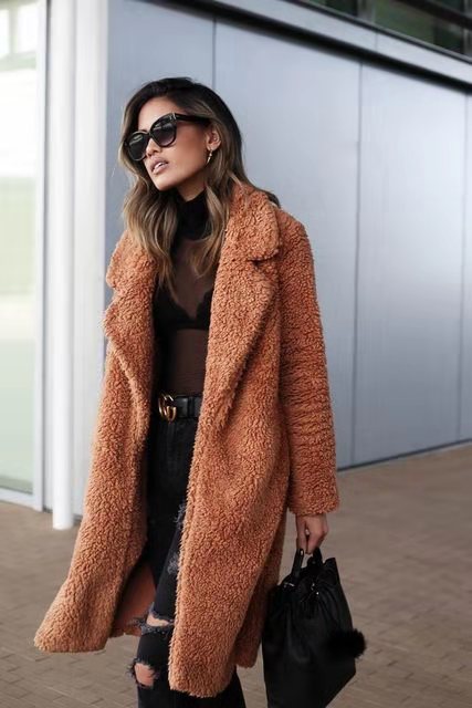 Chocolate - A woman wearing a cream-coloured, longline textured teddy coat with oversized lapels, styled over a grey t-shirt and blue jeans.