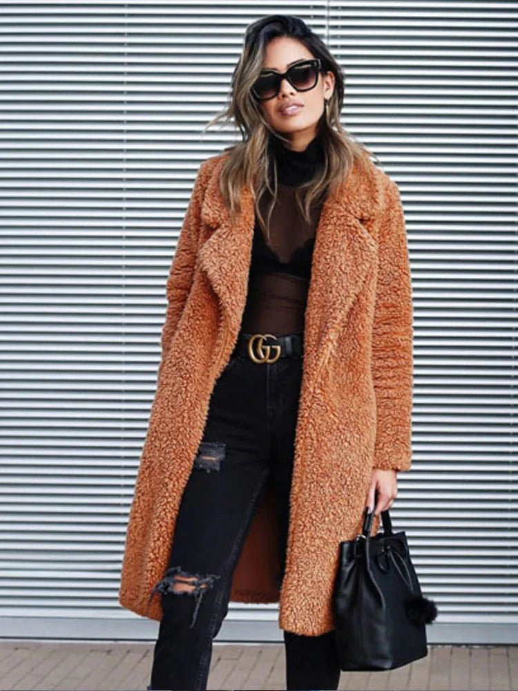 Chocolate - A woman wearing a cream-coloured, longline textured teddy coat with oversized lapels, styled over a grey t-shirt and blue jeans.