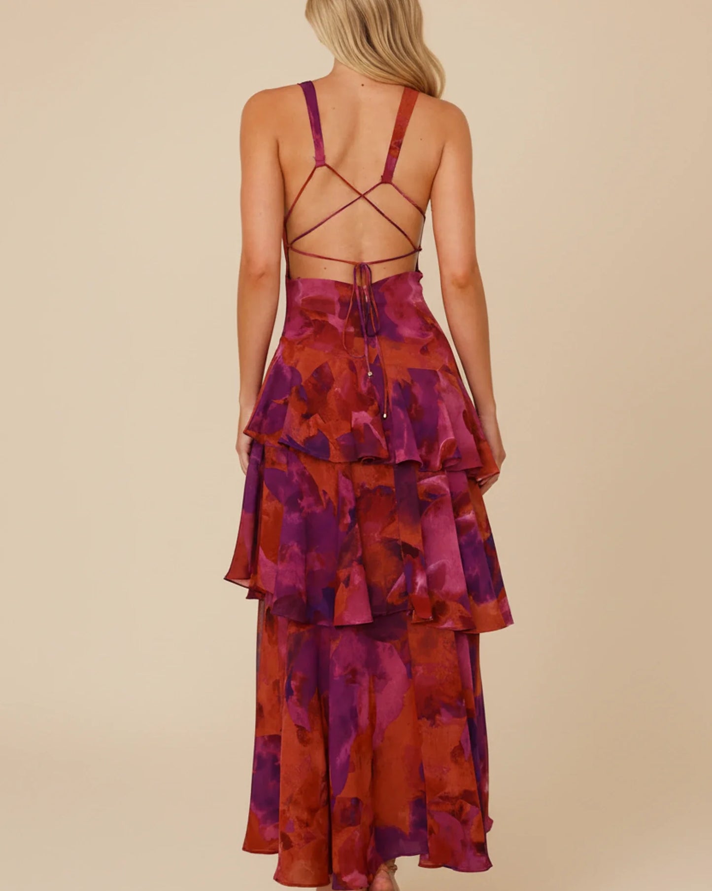 Purple - A woman models a formal plunging V-neck maxi dress featuring a vibrant teal and navy abstract print and a flowing tiered skirt.