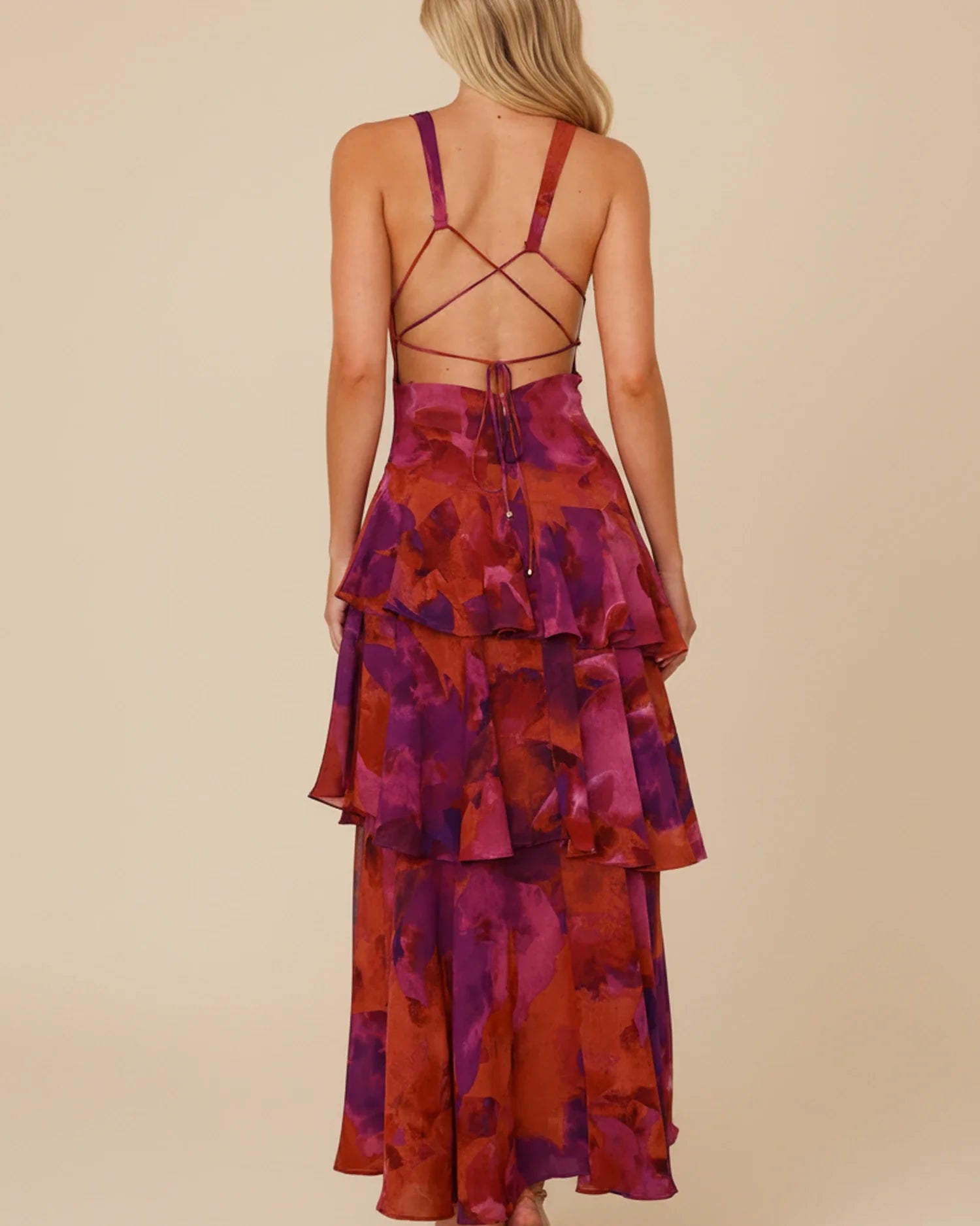 Purple - A woman models a formal plunging V-neck maxi dress featuring a vibrant teal and navy abstract print and a flowing tiered skirt.