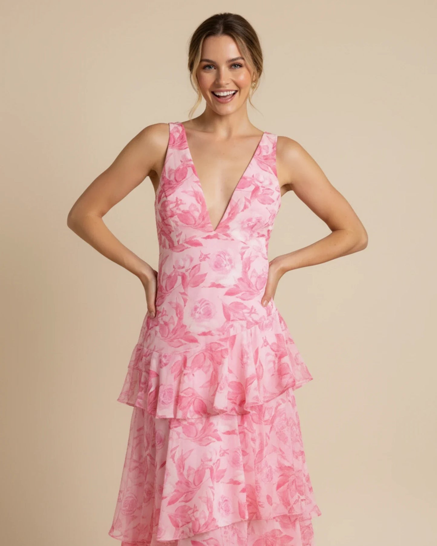 Pink - A woman models a formal plunging V-neck maxi dress featuring a vibrant teal and navy abstract print and a flowing tiered skirt.