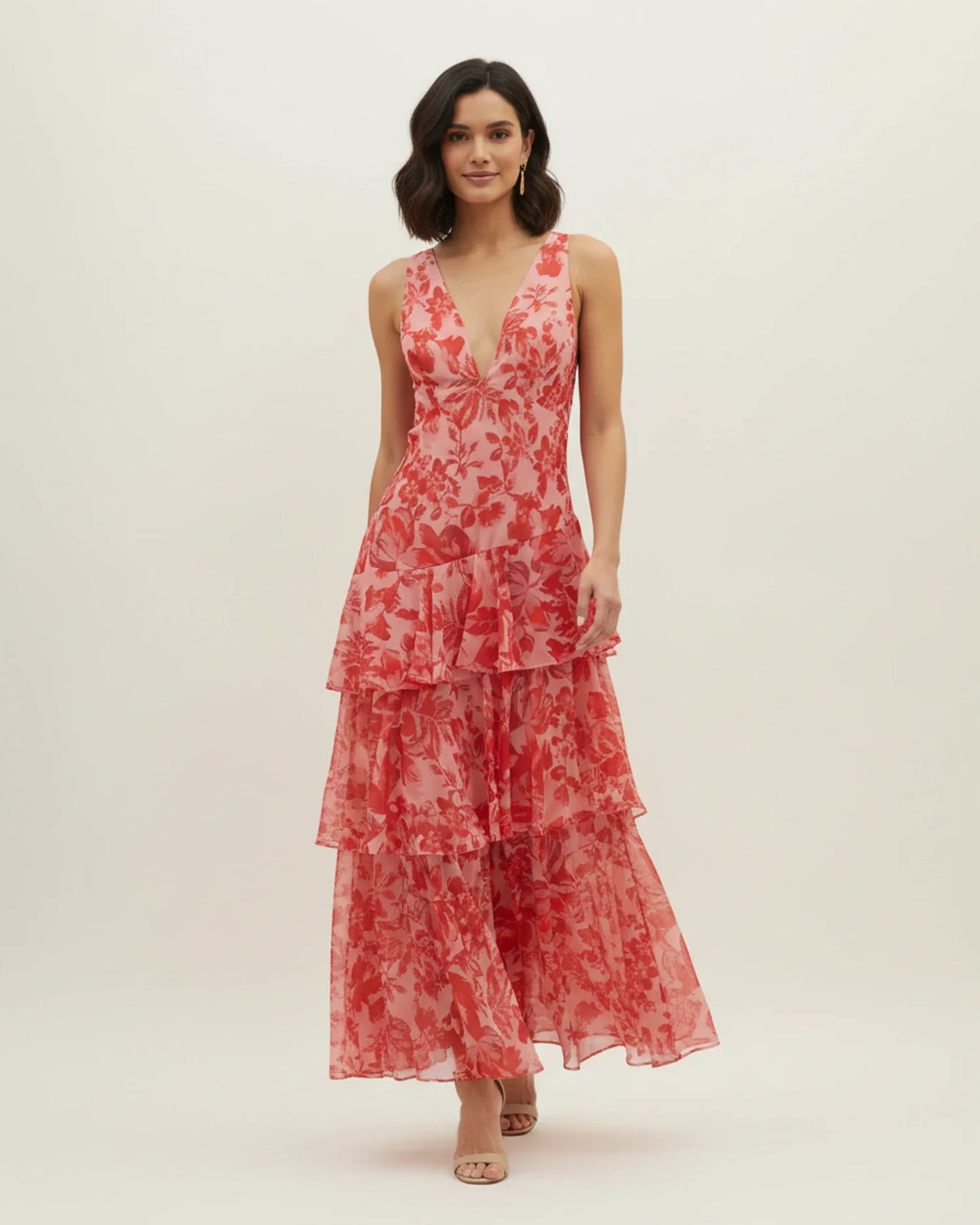 Red - A woman models a formal plunging V-neck maxi dress featuring a vibrant teal and navy abstract print and a flowing tiered skirt.