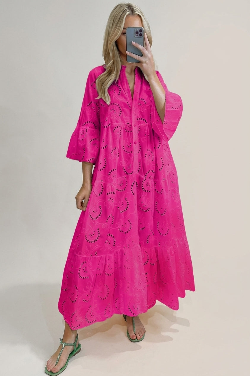 Pink - A woman wearing a white, tiered broderie anglaise maxi dress with three-quarter bell sleeves, a split v-neckline, and a relaxed silhouette, paired with green flat sandals.
