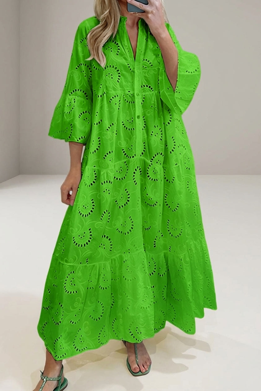 Green - A woman wearing a white, tiered broderie anglaise maxi dress with three-quarter bell sleeves, a split v-neckline, and a relaxed silhouette, paired with green flat sandals.