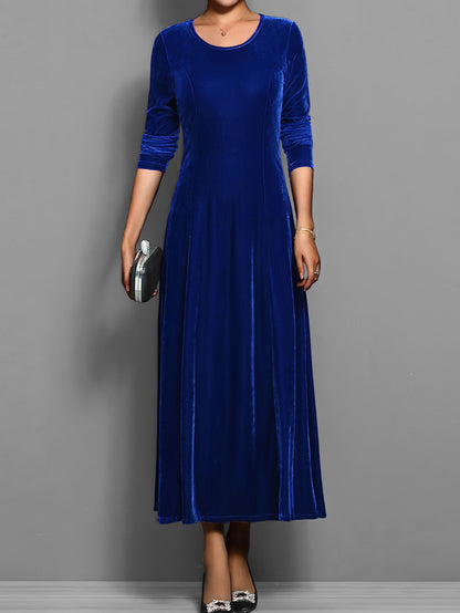 Blue - A woman wearing a long sleeve, A-line velvet maxi dress with vertical panelled seams.