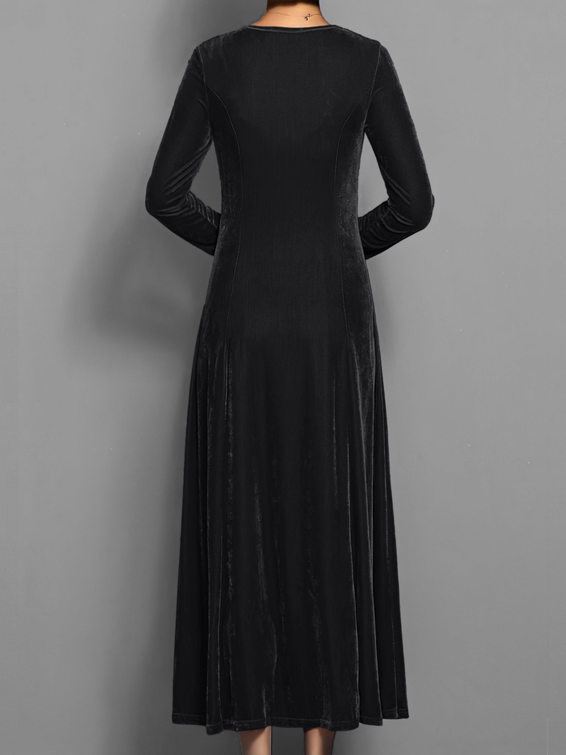 Black - A woman wearing a long sleeve, A-line velvet maxi dress with vertical panelled seams.