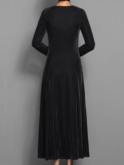 Black - A woman wearing a long sleeve, A-line velvet maxi dress with vertical panelled seams.