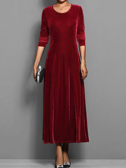 Red - A woman wearing a long sleeve, A-line velvet maxi dress with vertical panelled seams.
