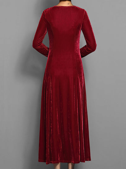 Red - A woman wearing a long sleeve, A-line velvet maxi dress with vertical panelled seams.