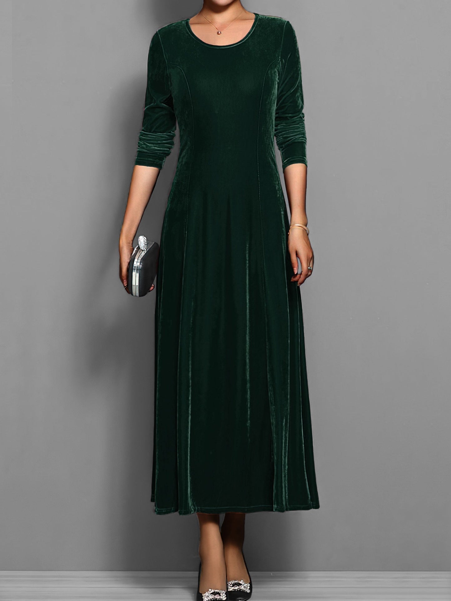 Green - A woman wearing a long sleeve, A-line velvet maxi dress with vertical panelled seams.