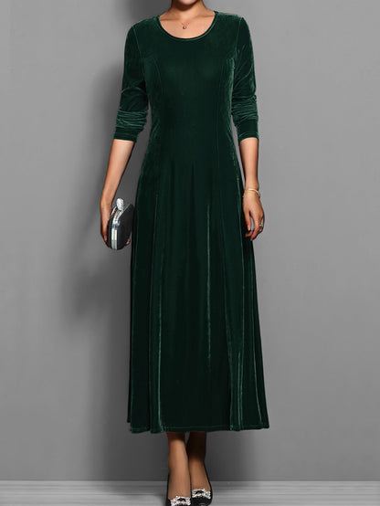 Green - A woman wearing a long sleeve, A-line velvet maxi dress with vertical panelled seams.